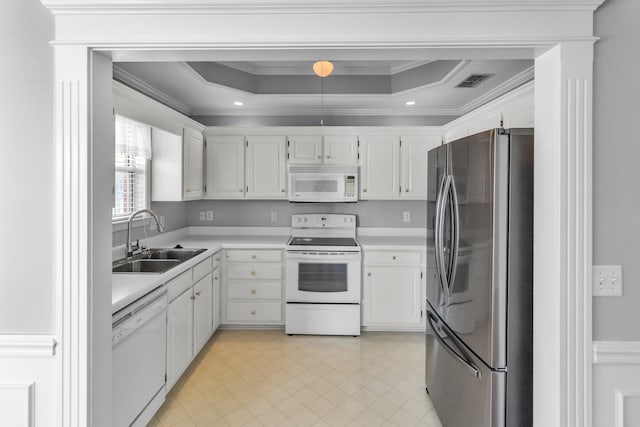 kitchen with ornamental molding, white appliances, light countertops, a raised ceiling, and a sink