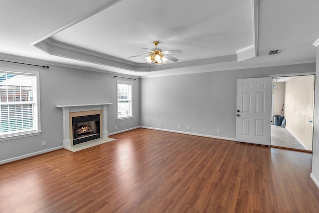 unfurnished living room featuring a tray ceiling, a ceiling fan, wood finished floors, and visible vents