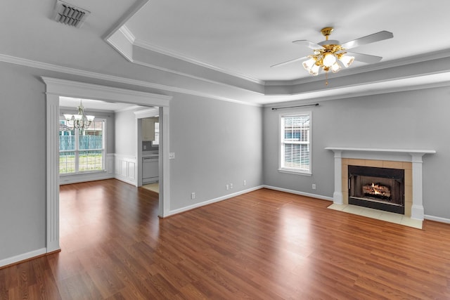 unfurnished living room with a tray ceiling, a wealth of natural light, and visible vents
