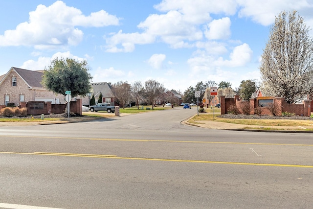 view of street featuring traffic signs, sidewalks, a residential view, and curbs
