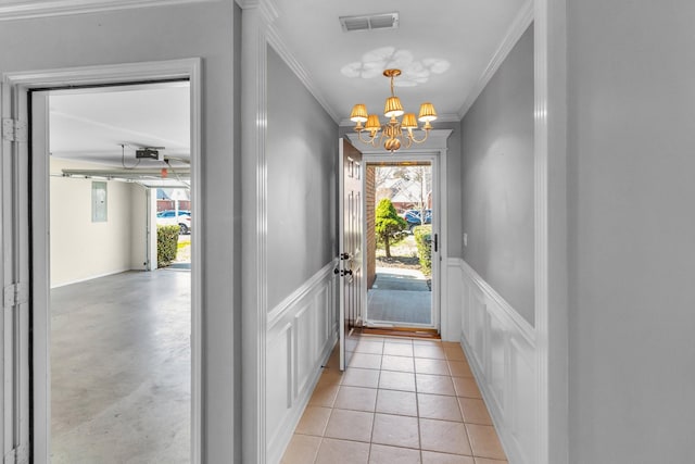 doorway with visible vents, a wainscoted wall, a notable chandelier, and light tile patterned flooring