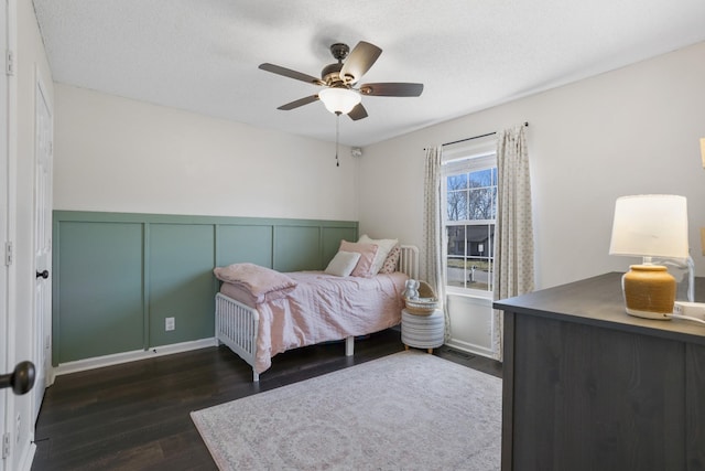 bedroom featuring visible vents, a wainscoted wall, a ceiling fan, a textured ceiling, and dark wood finished floors