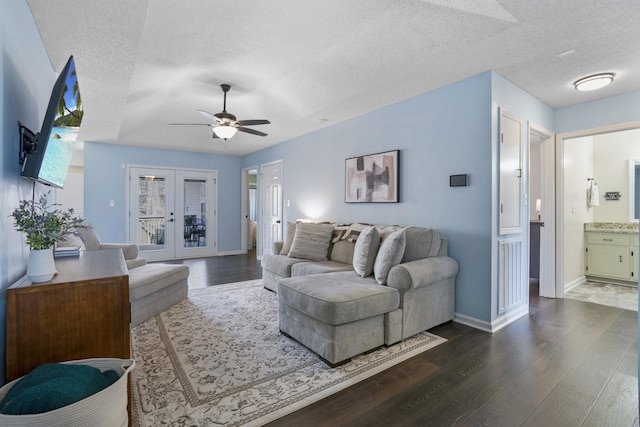 living area with a ceiling fan, baseboards, dark wood-type flooring, french doors, and a textured ceiling