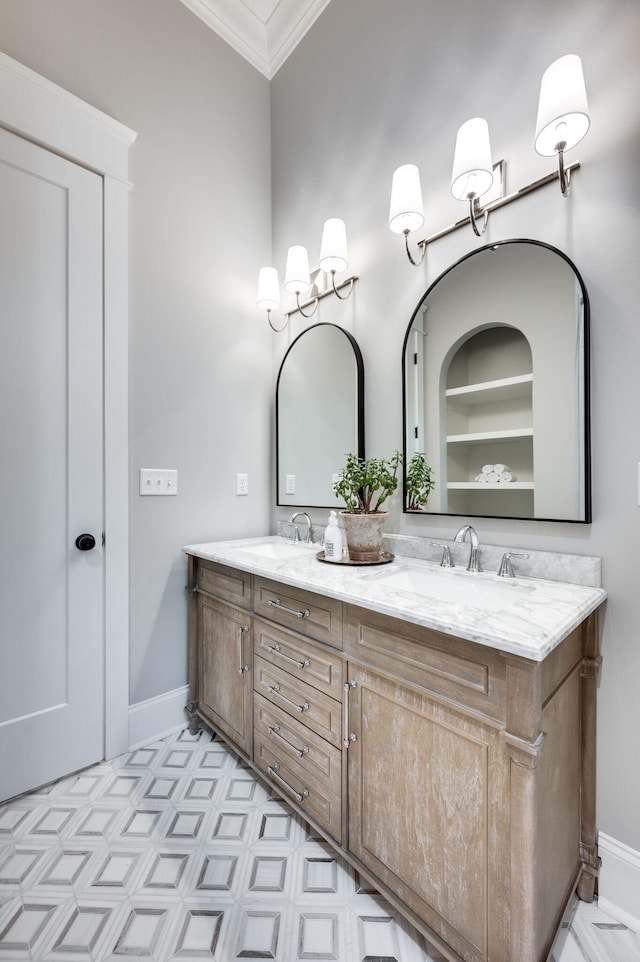 bathroom with double vanity, crown molding, baseboards, and a sink