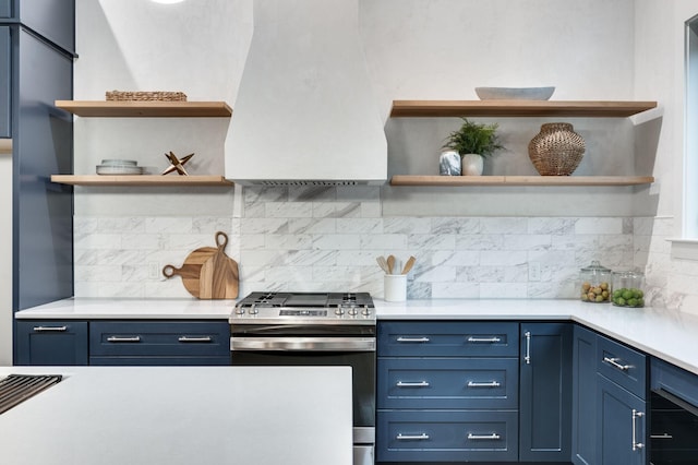 kitchen featuring open shelves, custom range hood, blue cabinets, stainless steel gas stove, and backsplash