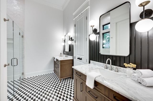 full bathroom with a shower stall, crown molding, baseboards, two vanities, and a sink