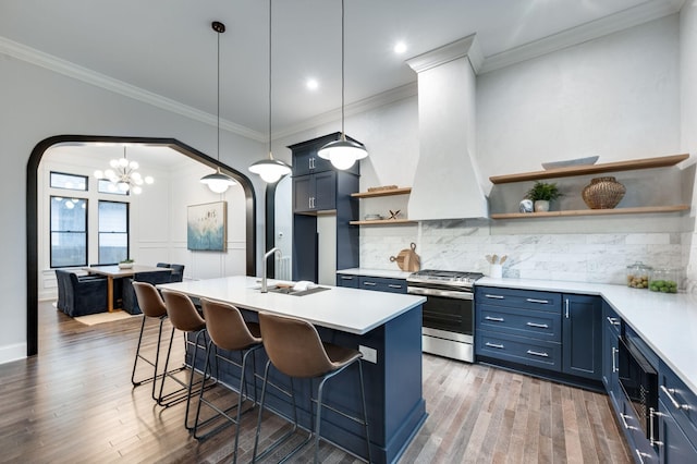 kitchen featuring stainless steel gas range, open shelves, blue cabinetry, arched walkways, and a sink