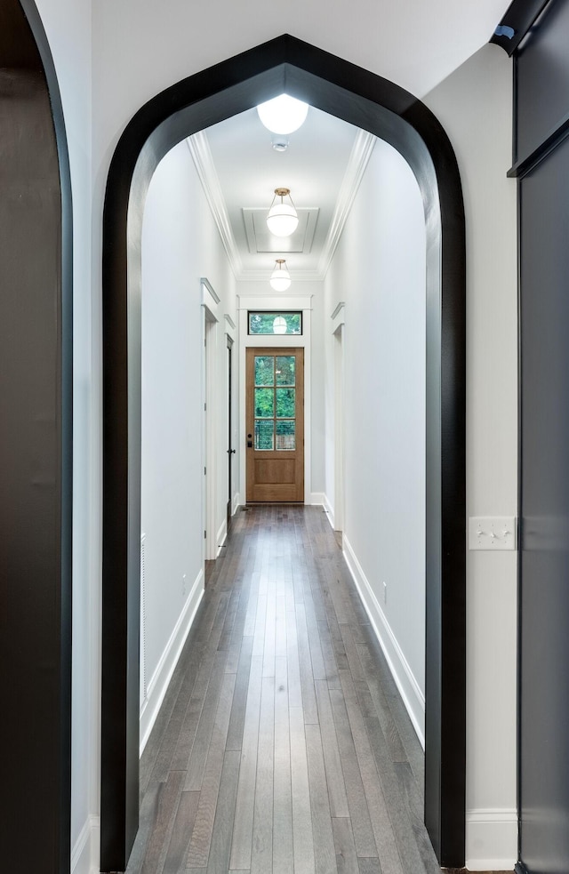 interior space featuring baseboards, arched walkways, dark wood-type flooring, and crown molding