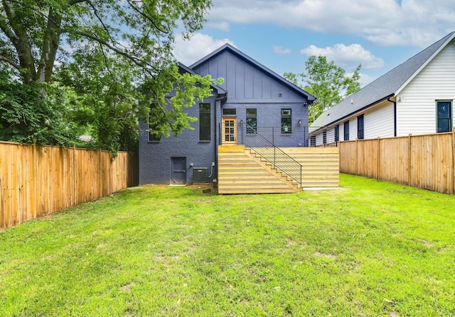 rear view of property with stairs, a yard, a fenced backyard, and board and batten siding