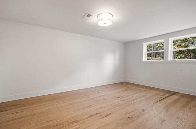 spare room with baseboards, visible vents, and light wood finished floors