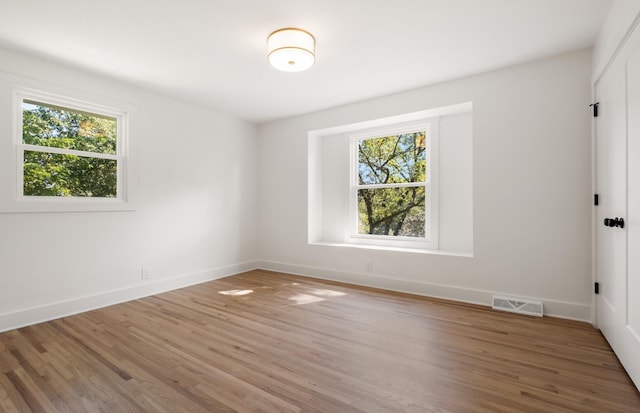 unfurnished room featuring visible vents, a healthy amount of sunlight, baseboards, and light wood-style floors