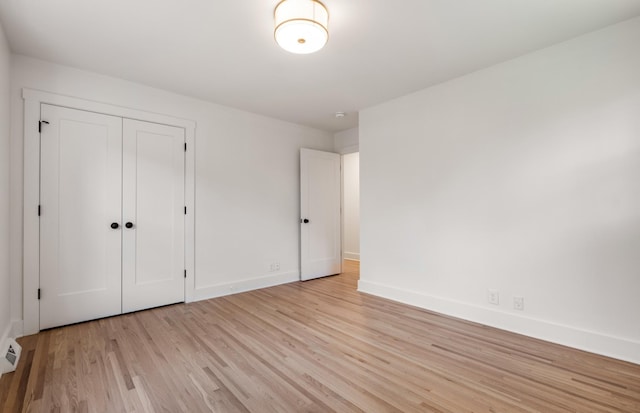 unfurnished bedroom with a closet, light wood-style flooring, and baseboards