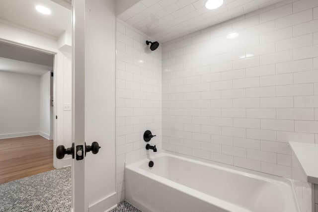 bathroom featuring washtub / shower combination, baseboards, and wood finished floors