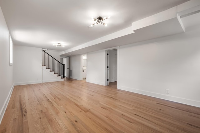 interior space featuring stairs, light wood-style floors, and baseboards