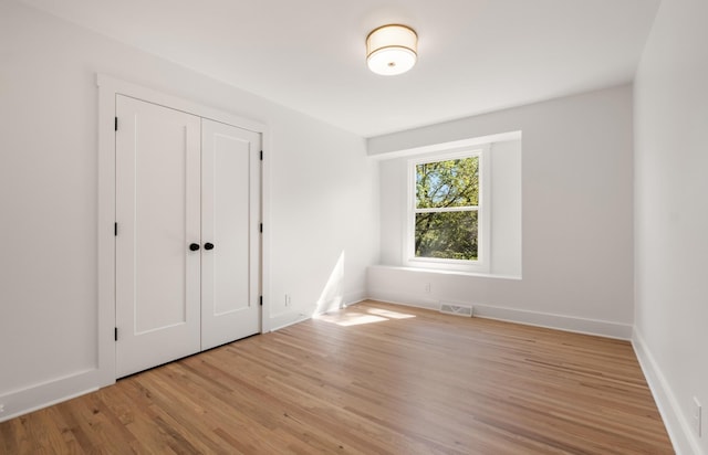 unfurnished bedroom with visible vents, baseboards, a closet, and wood finished floors