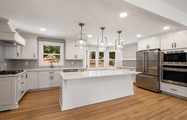 kitchen with a sink, stainless steel appliances, custom range hood, and light countertops