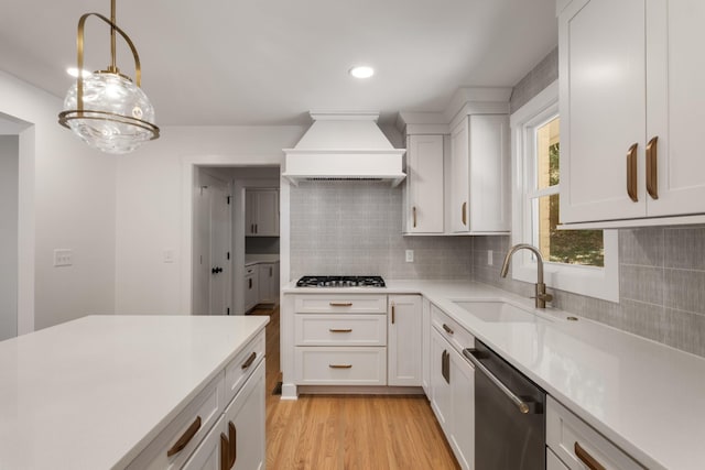 kitchen featuring custom exhaust hood, light wood-style flooring, a sink, stainless steel appliances, and light countertops