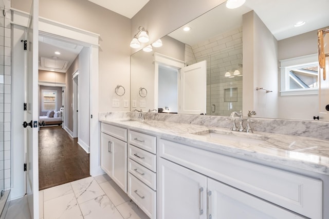 ensuite bathroom with a shower stall, double vanity, marble finish floor, and a sink