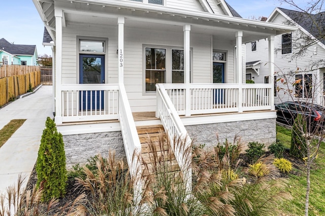 entrance to property featuring a porch and fence