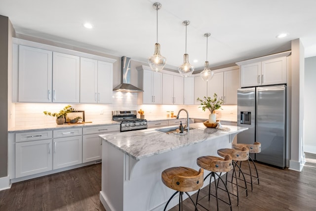 kitchen with a sink, dark wood-style floors, appliances with stainless steel finishes, wall chimney exhaust hood, and white cabinets