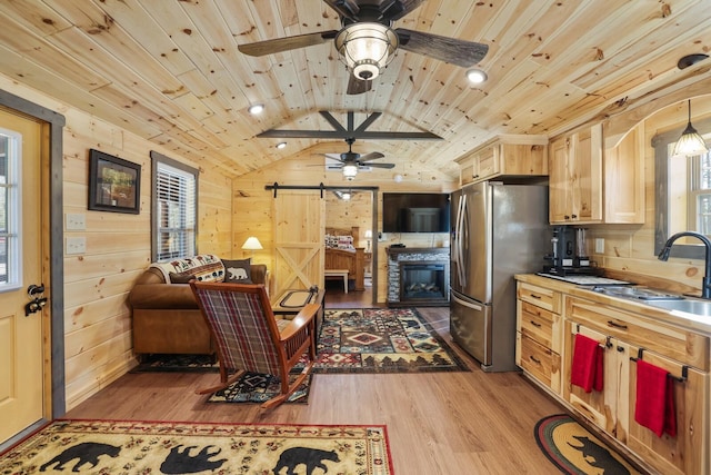 kitchen with wood ceiling, lofted ceiling, a barn door, freestanding refrigerator, and a sink