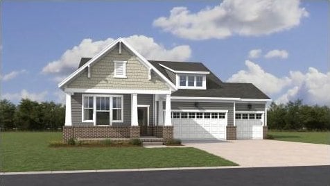 craftsman-style home with a front yard, brick siding, a garage, and driveway