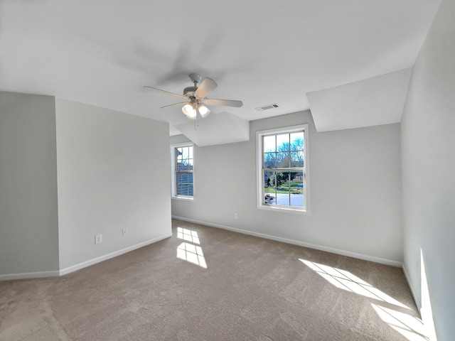 carpeted empty room featuring a ceiling fan, baseboards, visible vents, and a wealth of natural light