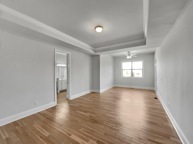 unfurnished room featuring ceiling fan, baseboards, a tray ceiling, and wood finished floors