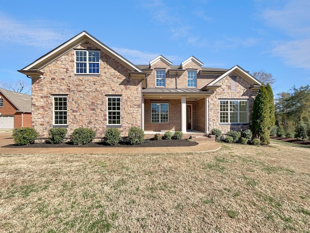 view of front of property with metal roof, brick siding, a front lawn, and a standing seam roof