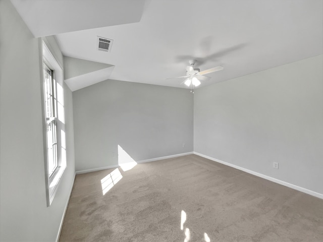 carpeted empty room with visible vents, baseboards, a ceiling fan, and vaulted ceiling