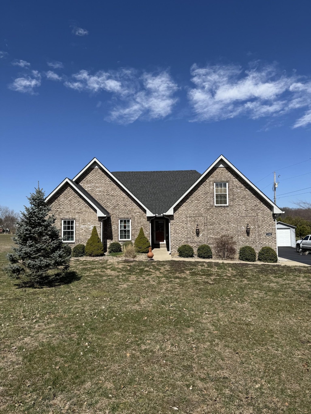 view of front of home with a garage, brick siding, and a front yard