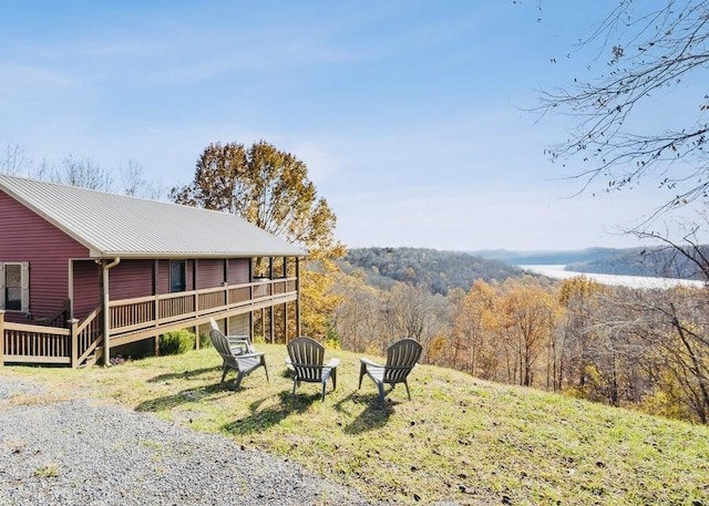 view of yard featuring a deck with water view and a view of trees