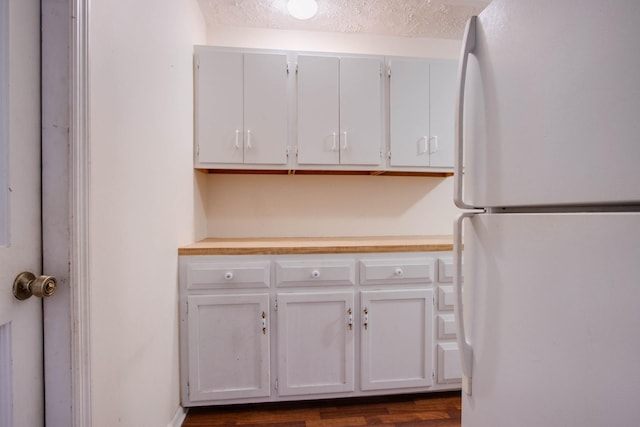 kitchen featuring white cabinetry, light countertops, freestanding refrigerator, and a textured ceiling