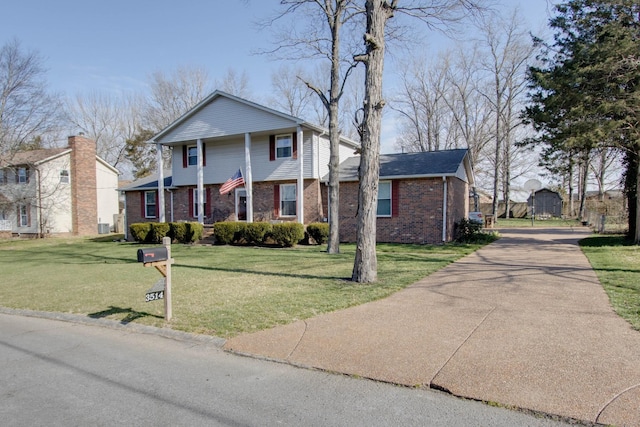 view of front of house with a front yard, concrete driveway, and brick siding