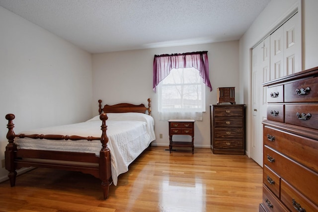 bedroom featuring light wood-style floors, baseboards, and a textured ceiling