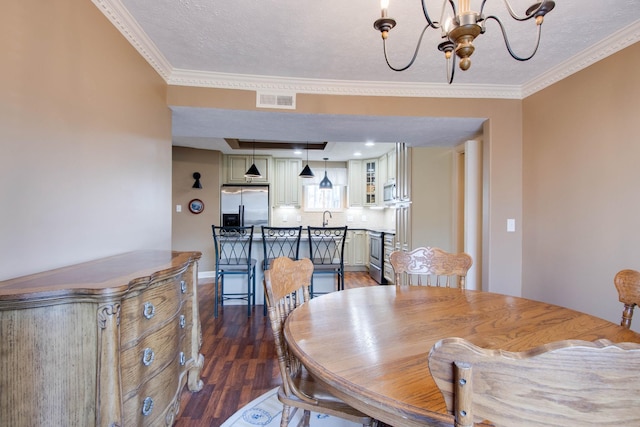 dining space with a notable chandelier, visible vents, crown molding, and wood finished floors