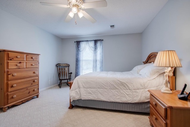 bedroom with a ceiling fan, baseboards, visible vents, a textured ceiling, and light carpet