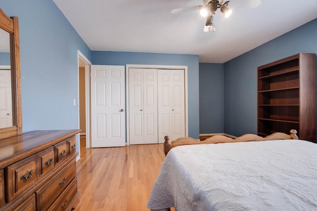 bedroom featuring baseboards, light wood-style flooring, ceiling fan, a closet, and a textured ceiling