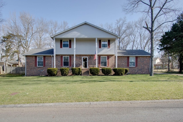 view of front of house featuring a front yard, fence, and brick siding