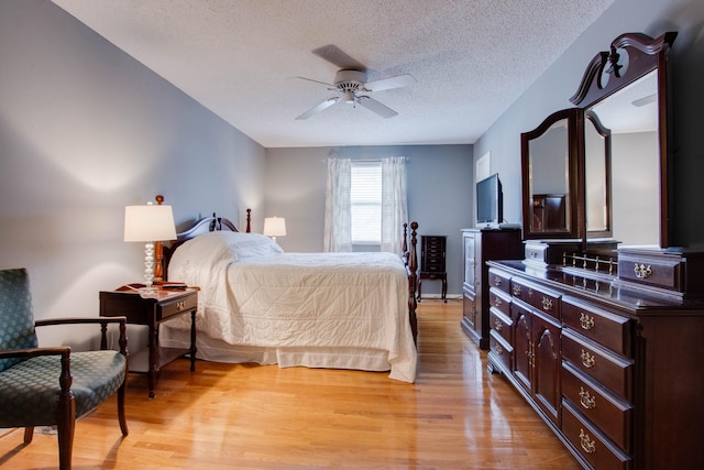 bedroom featuring a textured ceiling, light wood-style flooring, and a ceiling fan