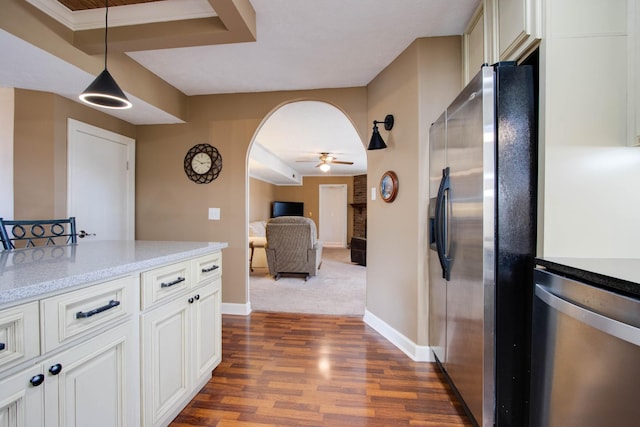 kitchen with dark wood finished floors, hanging light fixtures, appliances with stainless steel finishes, arched walkways, and a ceiling fan