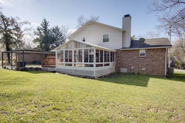 rear view of property with a sunroom, a chimney, crawl space, a lawn, and brick siding