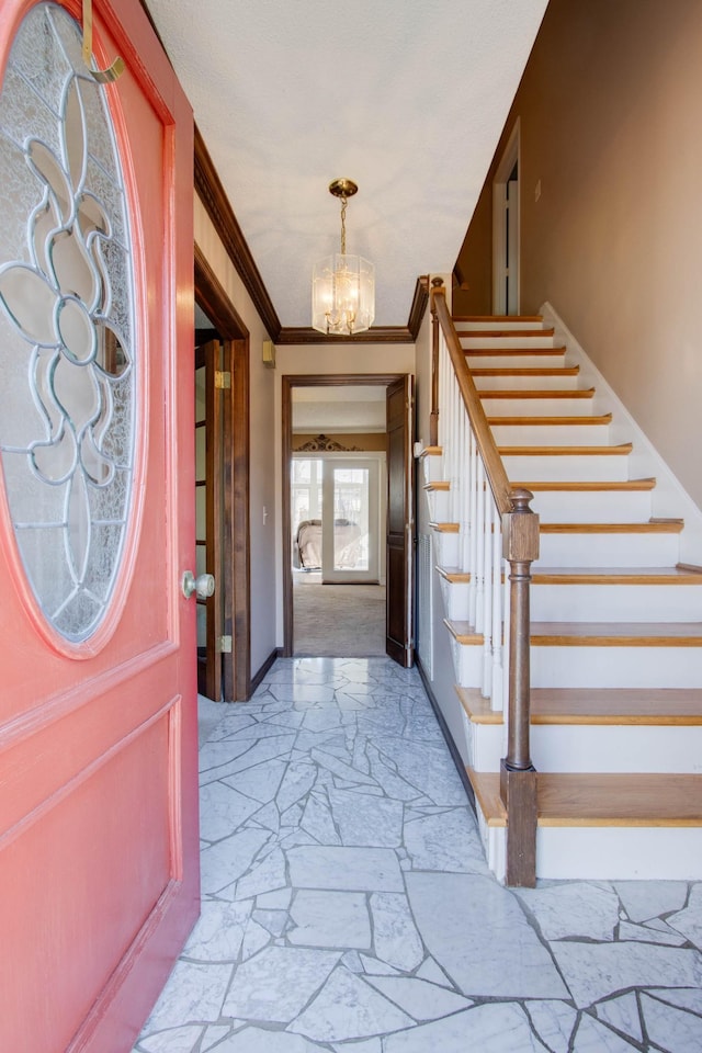 entryway featuring stairway, baseboards, an inviting chandelier, and crown molding