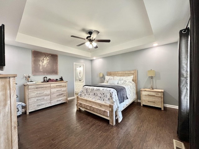 bedroom with visible vents, a raised ceiling, and dark wood-type flooring