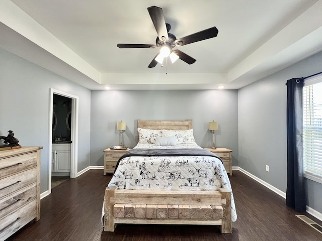 bedroom with a tray ceiling, baseboards, dark wood-type flooring, and a ceiling fan