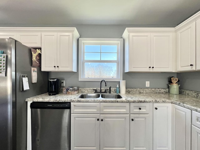 kitchen with a sink, appliances with stainless steel finishes, light countertops, and white cabinetry