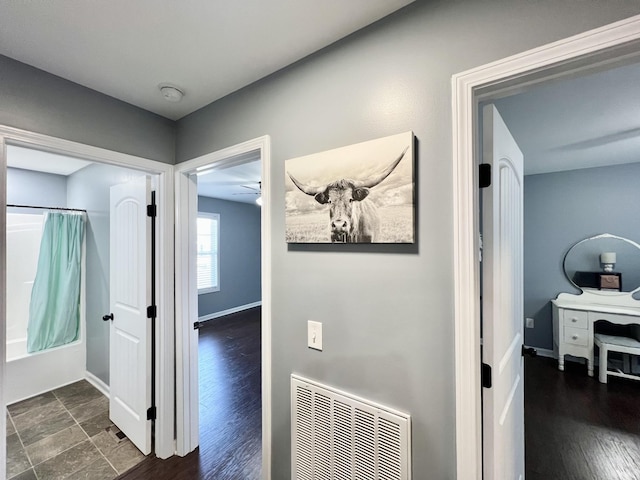 corridor featuring visible vents, dark wood-type flooring, and baseboards