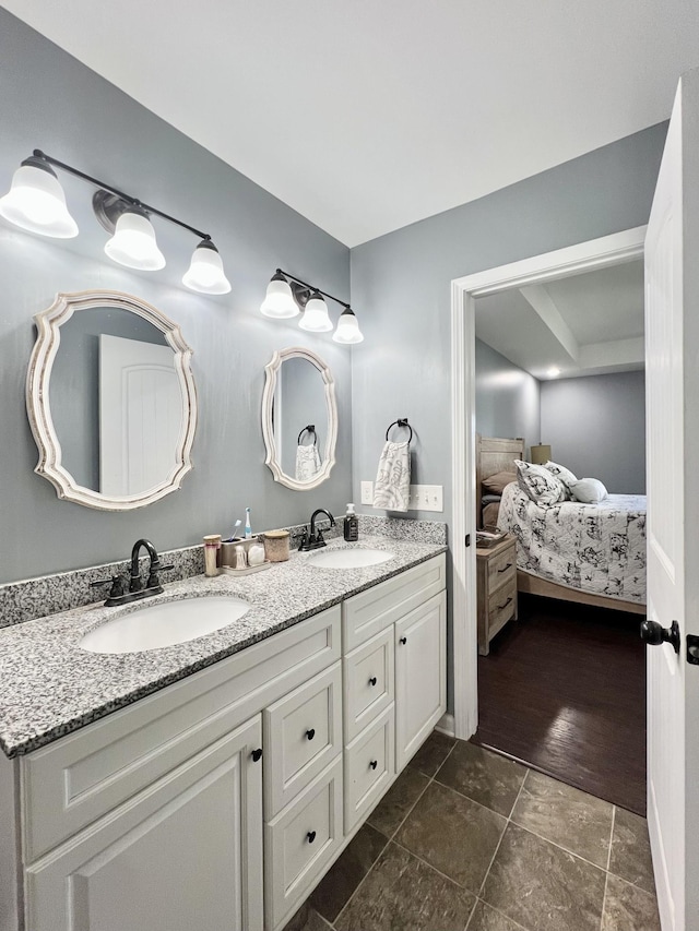 full bath with double vanity, connected bathroom, and a sink