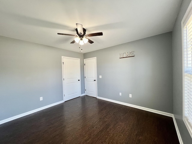 empty room with ceiling fan, baseboards, and dark wood-style flooring