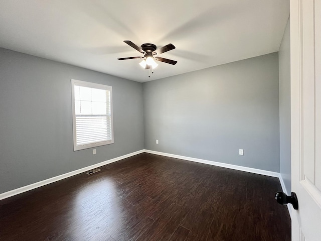 unfurnished room with dark wood-style floors, visible vents, a ceiling fan, and baseboards